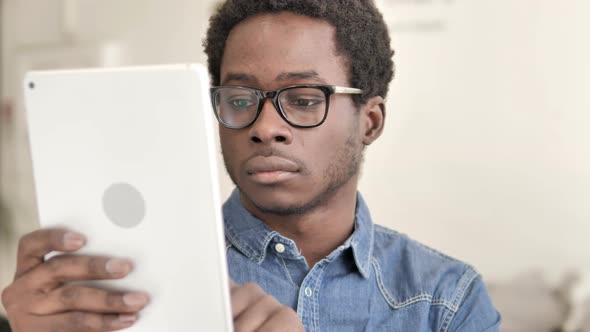 African Man Browsing and Scrolling on Tablet alt