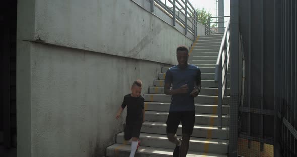 Diverse Father and Son Running on Concrete Staircase Together alt