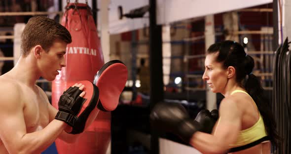 Female boxer practicing with trainer alt