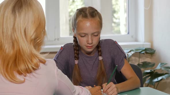 Cute Red Haired Schoolgirl Working on Her Art Project with the Help of Teacher alt