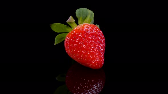 Perfect red strawberry rotating on a black background close up view.
