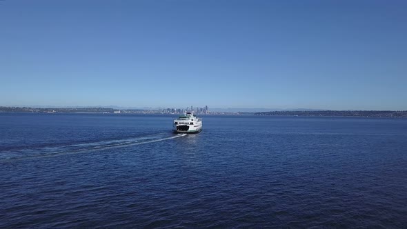 Aerial follow of the Seattle Ferry and downtown Seattle Washington city skyline in the distance. alt