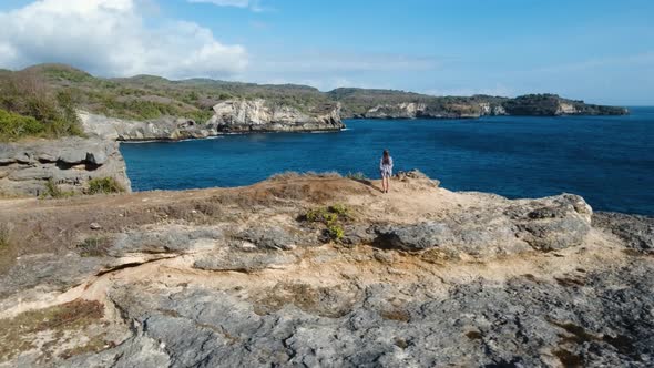 Girl Standing on a Cliff and Looking at the Sea. Bali, Indonesia alt