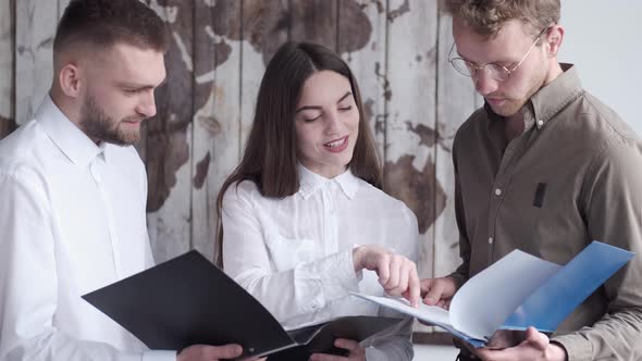 The Two Men and a Two Men and Woman Are Reading Some Documents in Folders in the Office alt