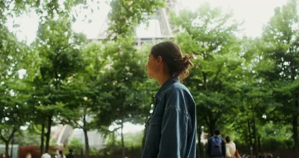 A Young Beautiful Woman Walks in the Park at the Foot of the Eiffel Tower alt