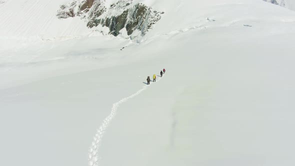 Group of Mountaineers Is Roped Together in Snowy Mountains. Aerial View alt