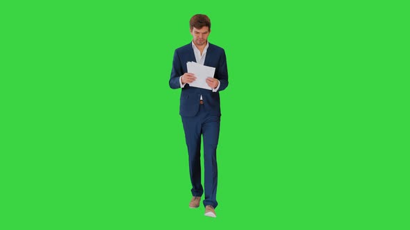 Serious Businessman Reading Documents or Report While Walking on a Green Screen, Chroma Key. alt
