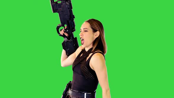 Girl in Black Tank Top and Leather Skirt Poses with a Gun in Hands Making Yeah on a Green Screen