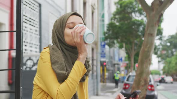 Woman wearing hijab drinking a takeaway coffee alt