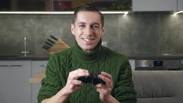 Happy Excited Man Gamer Holding Controller Playing Video Games While Sitting on Sofa in Living Room alt