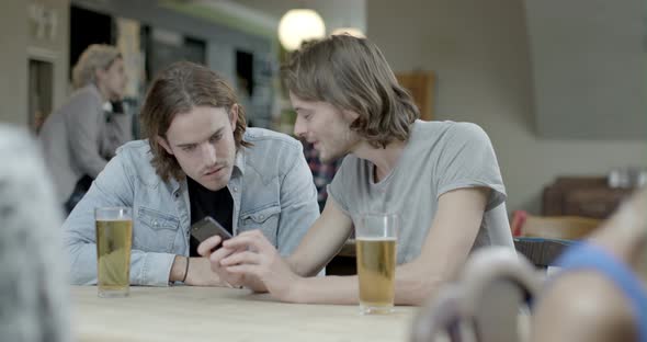 Men drinking beer and talking with each other while sitting in pub