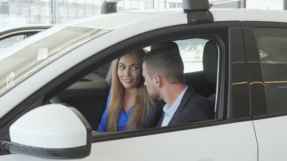 Beautiful Elegant Couple Sitting in a New Car at the Dealership