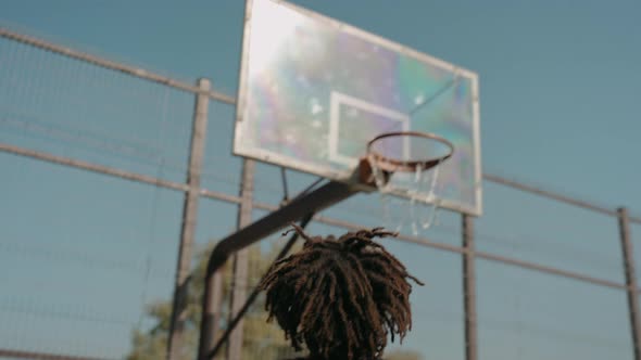 Black Man Trains Doing Slam Dunk Alone on a Street Basketball Court