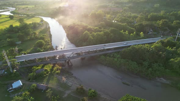 Aerial view of a car runing across the bridge over the river by drone