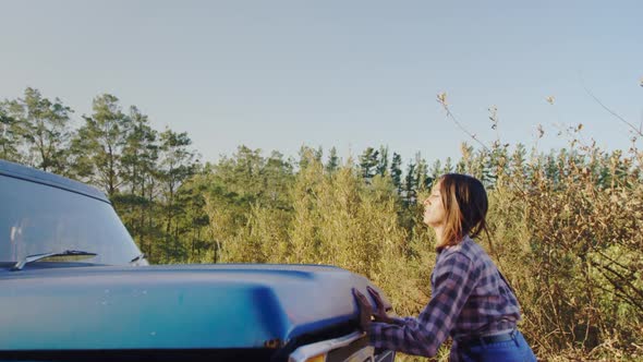 Young woman on a road trip next to pick-up truck alt