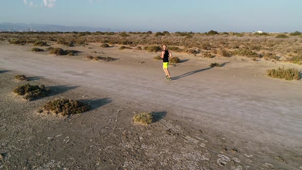 Drone Shot of Runner Jogging in Sandy Beach Desert