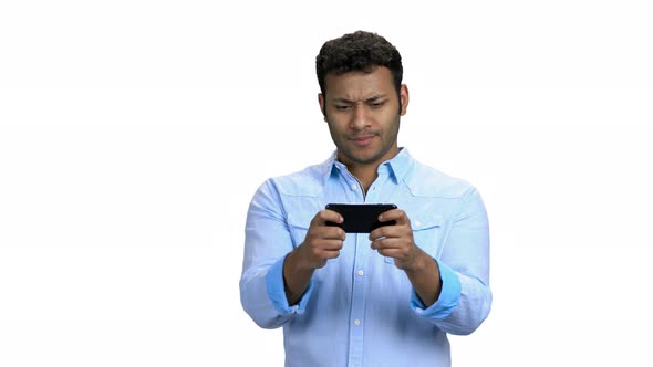 Young Concentrated Man Playing Game on Smartphone alt