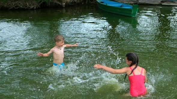 Little boy and girl splashing water on the lake. Outdoor recreation in summer.