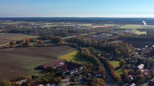 Smooth backward flight over a bavarian town in the fall season, idyllic living next to autumnal colo alt