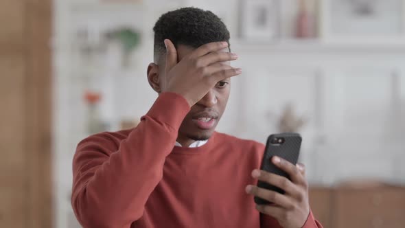 Portrait of African Businessman Reacting to Loss on Smartphone alt