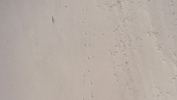 AERIAL: Top View of Sandy Beach with Footprints in the Sand alt