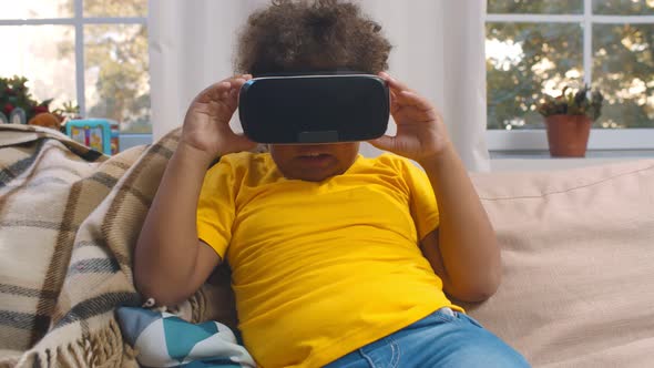 African Toddler Boy in Virtual Reality Headset Playing Video Game at Home alt