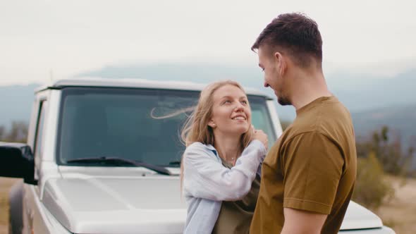 Young Traveler Couple on Road Trip in Mountains Standing Near Car