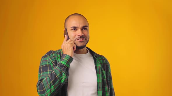 Worried Anxious Man Talking on Mobile Phone Against Yellow Background alt