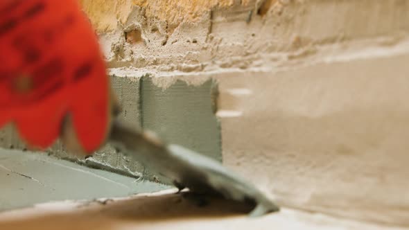 A Close Up of a Worker Puts a Trowel on the Floor of Plastering a Wall with a Floor