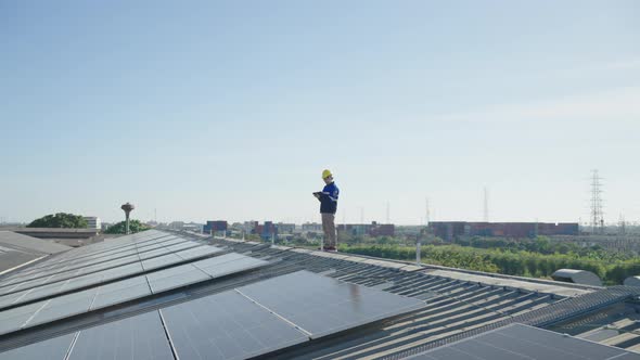 Asian technician inspection solar cell panels field of on roof top factory.