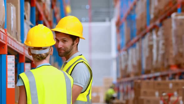 Male and female warehouse worker inspecting stock alt