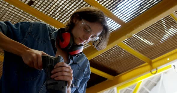 Female welder using drill machine in workshop 4k alt
