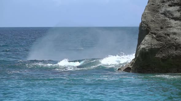 Sea Wave with Splashes Breaks over a Rock