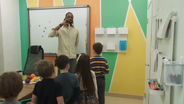 African American Teacher Teaches a Group of Children Aged 610 in a Classroom alt