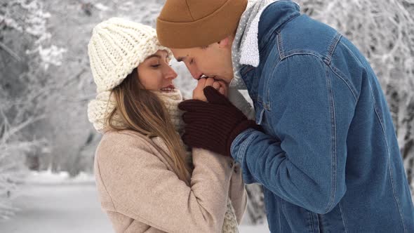A man warms his hands to a woman in a winter park. Family theme. Valentine's day alt