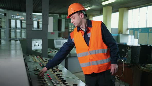 Worker Pressing Buttons on CNC Machine Control Board in Factory alt