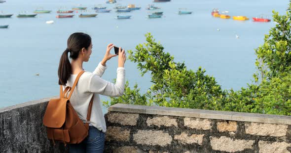 Woman go hiking and taking photo of the sea view alt