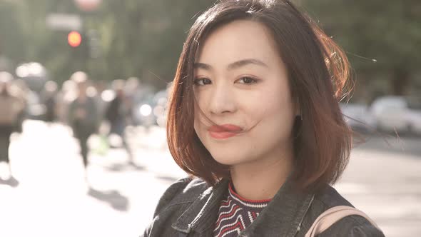 sweet and serene Asian woman in the street, smiling sweetly at the camera alt