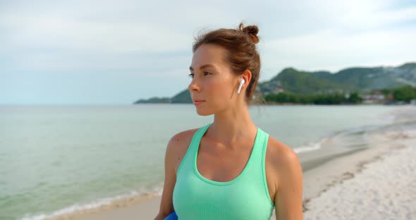 Sport Woman Walks on the Beach and Listening the Music Swop the Songs By Doubleclick on Headphones alt