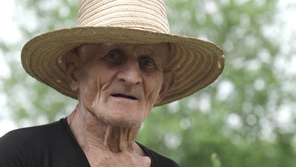 Portrait of Old Man with Tired Wrinkled Face in Straw Hat