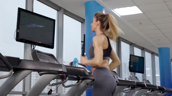 Young sporty Woman On Running Machine In Gym alt