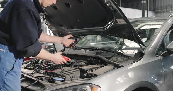 Car Mechanic Checking Power Voltage Of Car Battery In The Workshop alt