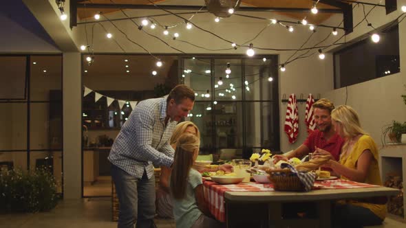 Happy family eating dinner together. alt