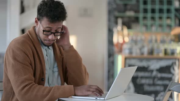 African Man Having Neck Pain While Using Laptop in Cafe alt