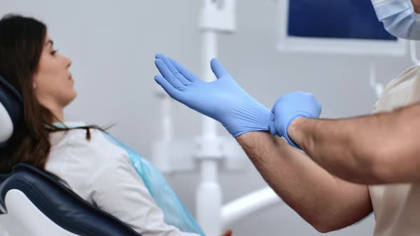 Closeup Professional Male Dentist Put on Blue Protective Rubber Gloves Patient Consult Checkup alt