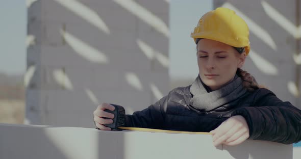 Confident Female Contractor Measuring Wall with Tape alt