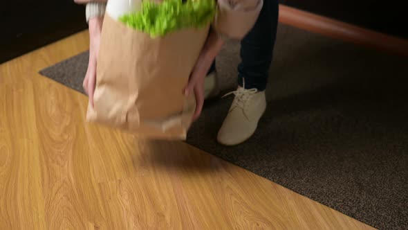 A bag of food falls when a woman places it on the floor alt