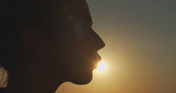 Close Up Female Face Profile Silhouetted on Evening Sky Setting Sun Slow Motion. Happy Woman Kissing
