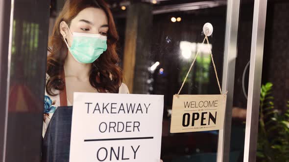 Business owner attractive young asian woman in apron hanging we're open sign. alt