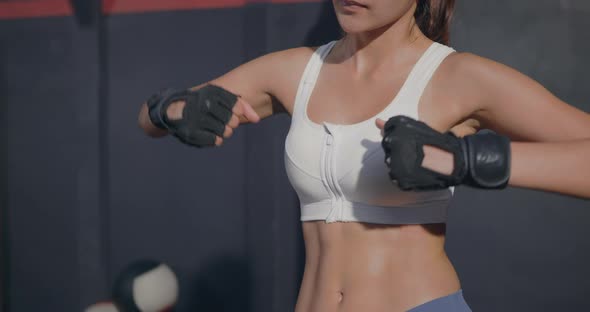 woman boxer standing inside a boxing gym fitness club studio with her punch hands alt